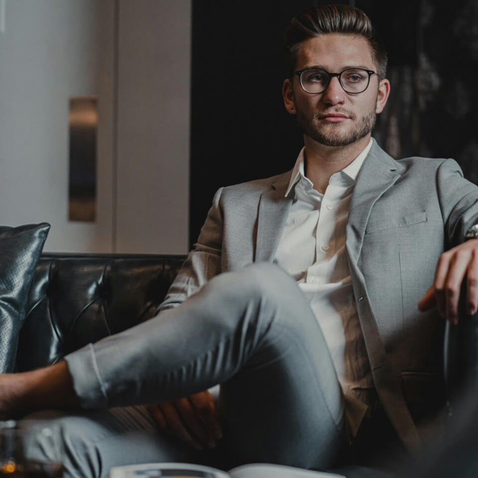 A man in suit and tie sitting on couch.